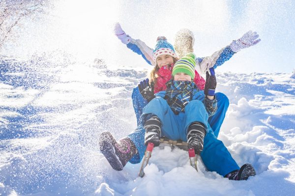 Happy family having fun together on the snowy mountain, on a sled.