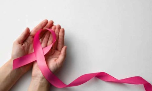 Woman holding pink ribbon on white background, top view with space for text. Breast cancer awareness concept